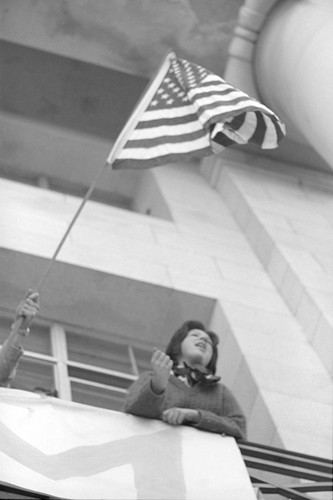 Student with American flag on Sproul Hall balcony