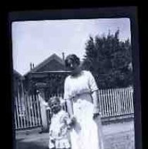 An unidentified woman and young girl standing in front of a hosue