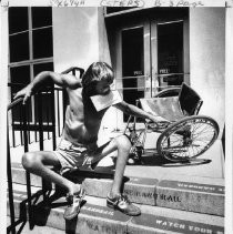 Gene Howard, a wheelchair athlete who competed in marathons, played tennis, and taught sports to handicapped children. He is shown with his wheelchair, sitting on steps leading into a large building