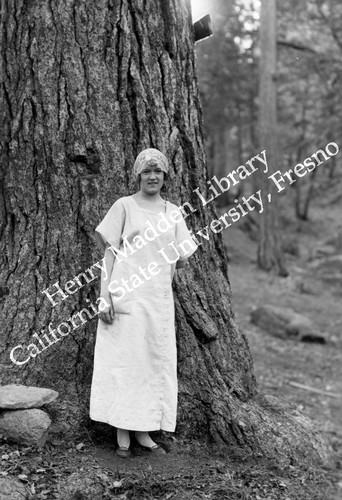 Young woman posing in front of pine