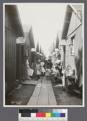 [Refugees posing among cottages at camp. Unidentified location.]