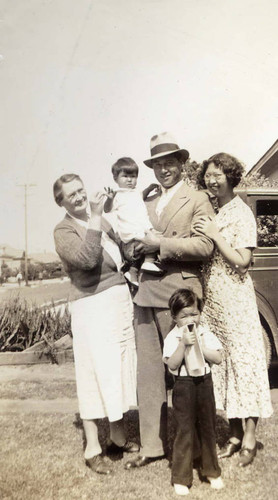 Jake's mother and Jake Siu holding Gilbert with wife Dorothy and Ronald standing in the lawn