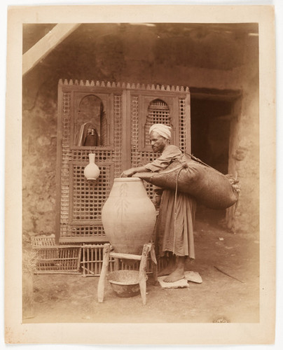 (Egyptian water carrier filling pot with woman behind screen)