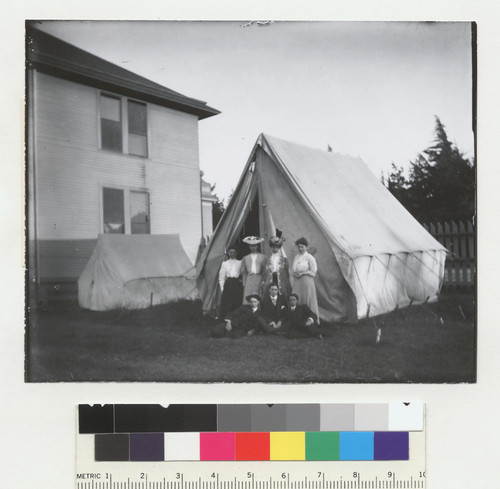 [Group of women and men posing before refugee tent. Unidentified location.]