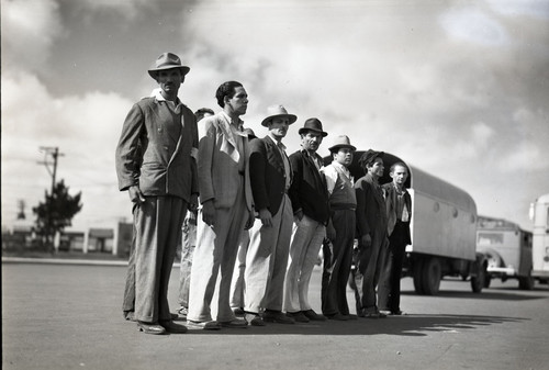 Ten Mexican workers standing near trucks