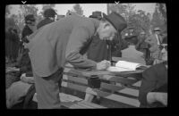Man writes in a register at the Iowa Picnic in Lincoln Park, Los Angeles, 1939