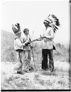 Two boys and a man wearing Native American headdresses at the Pacific Southwest Museum