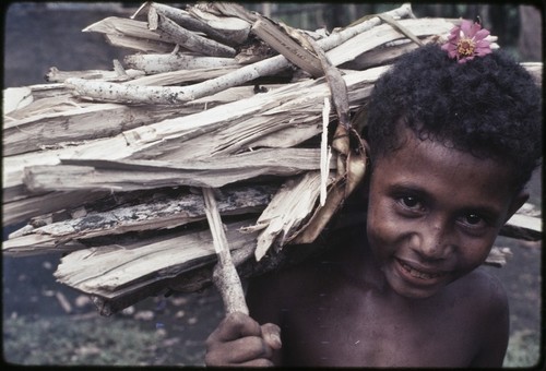 Young boy carries bundle of firewood