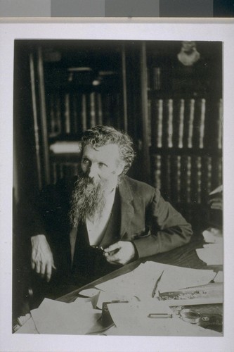 [John Muir seated at a desk.]