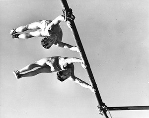 Two men practicing gymnastics from one of the playground bars