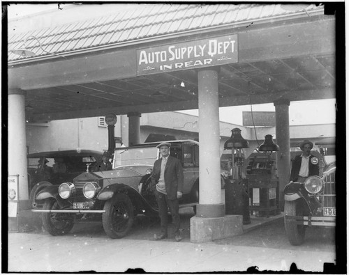Men standing next to cars at gas station