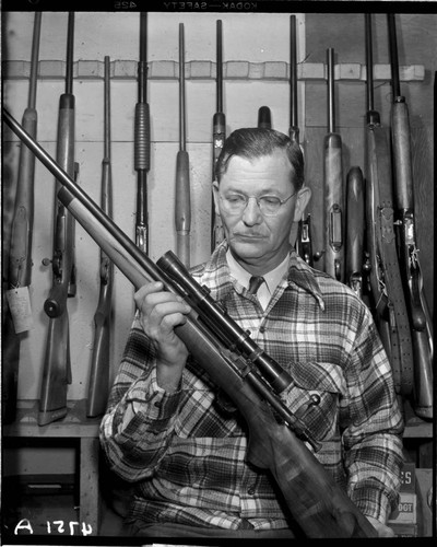 Man holding bolt action hunting rifle with scope