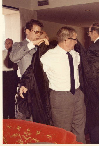 Dr. Larry Hornbaker assisting Clint Murchison with his robing