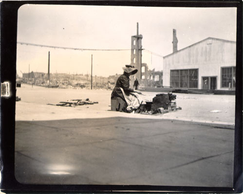 [Woman preparing a meal on an unidentified street]