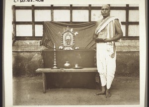 Götzenpriester neben seinem Götzen und seinen Opfergeräten vor dem Tempel in Udapi
