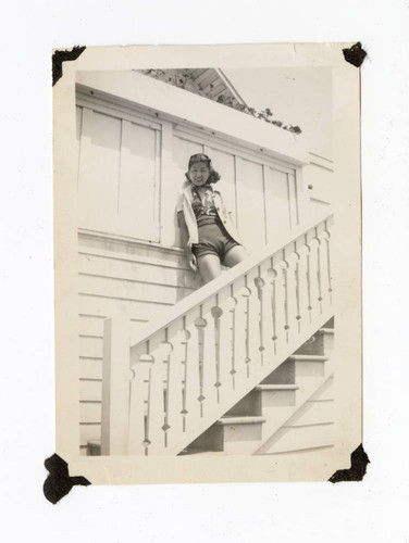 Young woman standing on the stairs of a house at the beach