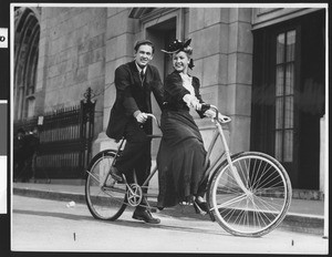 Couple on a bicycle built for two, ca.1900