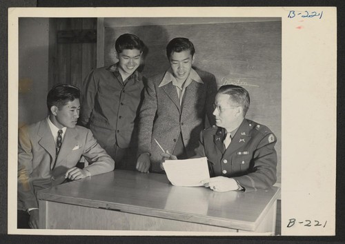 Lieutenant Eugene Bogard, Commanding Officer of the Army Registration team, explains to young evacuees details of volunteering in the Army Combat team, which is being organized and made up entirely of Japanese-Americans. Photographer: Stewart, Francis Manzanar, California