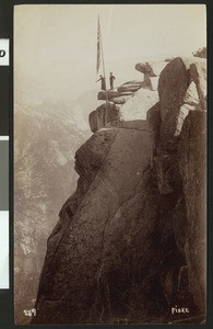 People and flagpole near the protective railing at Glacier Point in Yosemite National Park, ca.1900