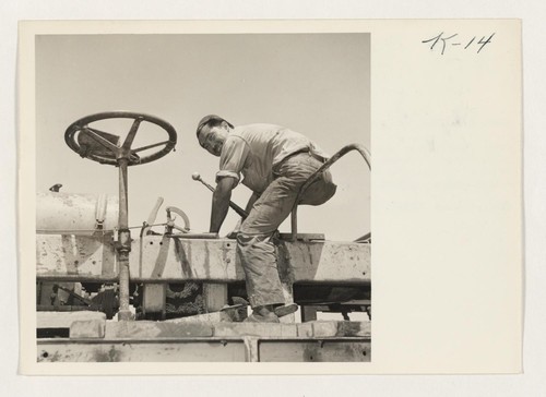 Repairing a potato digger on the Roscoe Zukerman farm at Camp #21, Mandeville Island, Stockton, California, is Toru Okazaki, formerly