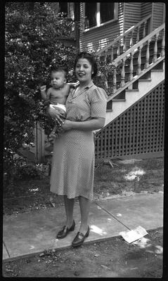 Woman standing in front of house holding baby
