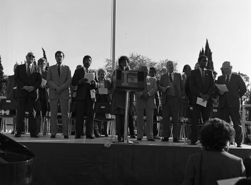 Julian Bond, Diane Watson, Kenneth Hahn and others standing on an outdoor stage, Inglewood, California, 1985