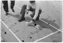 Sports official making marks on the track at a meet between UCLA and USC, Los Angeles, 1937