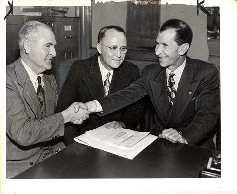 [Patrolman James J. McGovern (left) shaking hands with Fireman Barney Lenhart (right), Ira G. Thompson (center)]