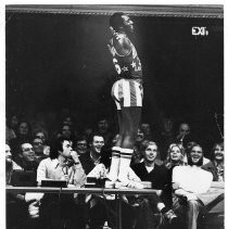 Meadowlark Lemon of the Harlem Globetrotters, standing on the announcer's table during a game