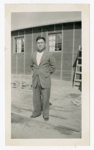 Satoru Maeda standing in front of barrack at Heart Mountain