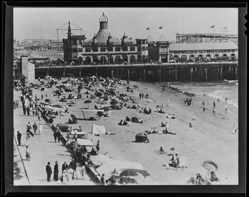 People on beach next to Looff Pleasure Pier and Santa Monica Pier