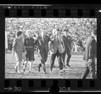 Nancy Reagan, Pat Nixon, Richard Nixon and Ronald Reagan walking across field at 1969 Rose Bowl game