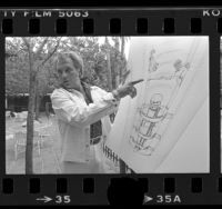 Evel Knievel showing diagram of his drop from airplane stunt, 1977