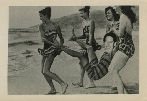Four women carrying man towards ocean