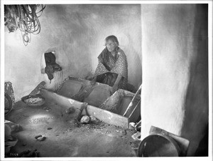 Hopi old Indian woman grinding corn for bread, ca.1900
