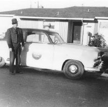 Dorlen McGuffee in uniform standing next to his Border Patrol car
