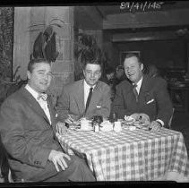 Three men sitting at a dining table in a restaurant