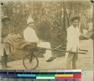 Ole Jensenius in an "Aero-Pousse" pushed and pulled by two Malagasy men, Madagascar