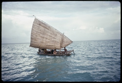 Canoe under woven pandanus sail, several passengers including women