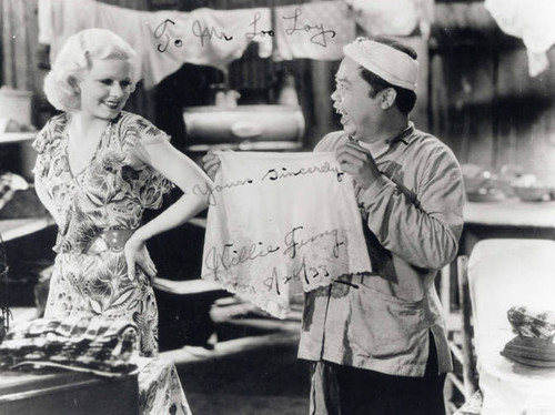 Movie scene with a blonde Caucasian woman and stereotypical Chinese man. Written on the photo is "To Mr. Loo Loy yours sincerely Willie Fung."