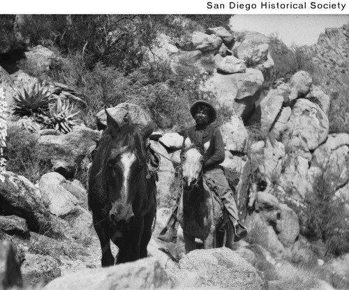 Sam Taylor riding a horse along a rocky trail at Warner Ranch