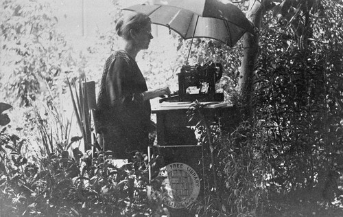 Photograph of Anne Hadden on library grounds writing a paper for American Library Association