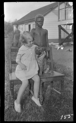 European girl on chair with dog, and Papua New Guinea boy behind