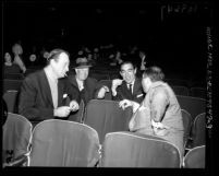 John Wayne, Maurice Chevalier, Anthony Quinn and Jerry Wald chatting in the empty seats of theater during 1958 Academy Awards rehearsals