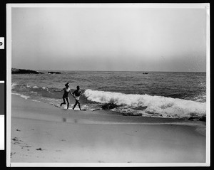 Couple running in the surf, Laguna Beach, ca.1950