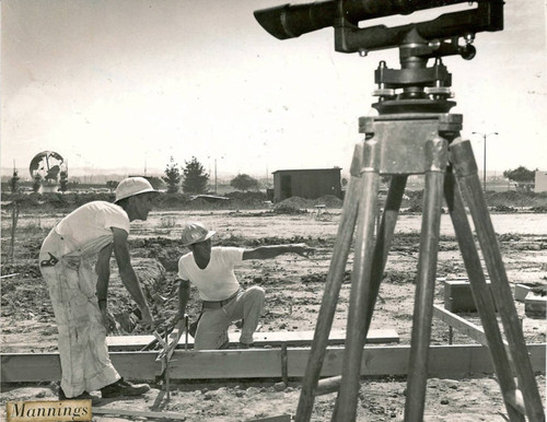 Two workers and surveying equipment during the construction of Mannings Cafeteria in Leisure World