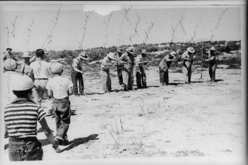 Men engaged in activity with sticks and string