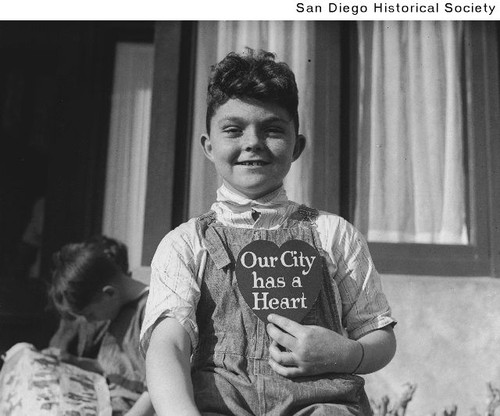 A young boy from a children's home holding a sign that reads "Our City has a Heart"