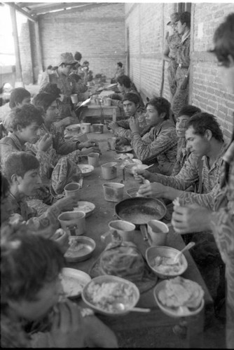 Soldiers eating on long table, Guatemala, 1982