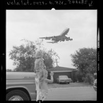 Esther F. Hall and granddaughter watching 747 jetliner, on route to LAX, fly over their home in Los Angeles, Calif., 1973